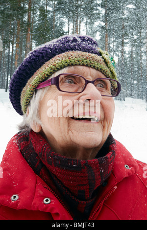 Smiling older woman watching snow fall Stock Photo