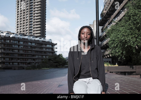 Portrait of a young woman sat outside at city housing estate