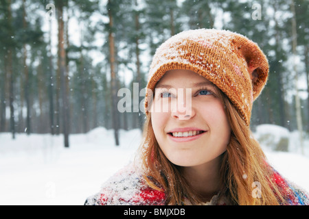 Smiling young woman watching snow fall Stock Photo