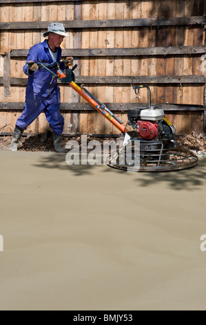 man levelling concrete base with power float Stock Photo