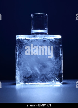 A  small glass on top of a frozen block of ice on a metal surface Stock Photo