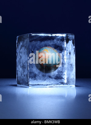 A frozen block of ice with a world globe frozen inside on a metal surface Stock Photo