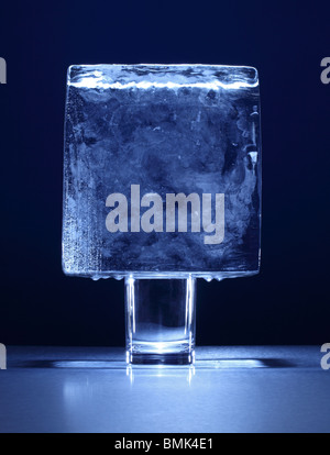 A frozen block of ice on top of a small glass Stock Photo