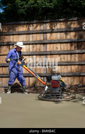 man levelling concrete base with power float Stock Photo