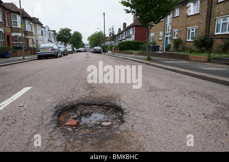 Pot holes in a suburban road in North London Stock Photo