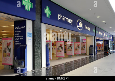 Green Pharmacy Cross signs above open plan entrances to Boots chemist retail business with beauty store in shopping centre mall Chelmsford England UK Stock Photo