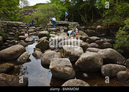 Children clambering over boulders in the East Dart River at Dartmeet. Stock Photo