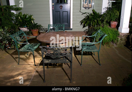 On the veranda four wrought iron chairs, a table and potted plants. Stock Photo