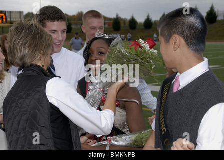Girl is presented with a bouquet of roses after she was crowned Homecoming queen at a high school homecoming football game Stock Photo