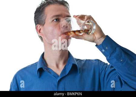 A man in a blue dress shirt, drinking pop from a glass with ice, isolated on white. Stock Photo