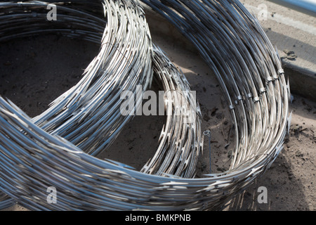 Bundled rolls of stainless steel razor wire spirals for security fence at correctional facility in central Florida Stock Photo