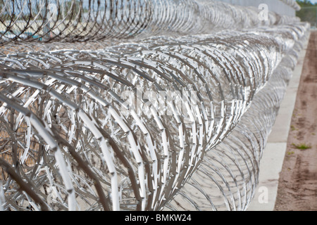 Rolls of stainless steel razor wire spirals keep prisoners away from chain link fence at correctional facility in Florida Stock Photo