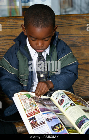 African American boy children child reading in front of Cracker Barrel Store and Restaurant .Florida United States  MR  © Myrleen Pearson Stock Photo