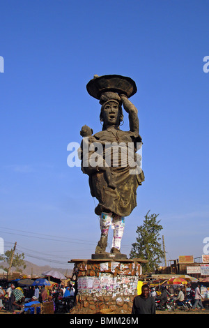 Nigeria, Jos, Statue representing a woman and her baby in the arm, with advertising posters stuck on her legs Stock Photo