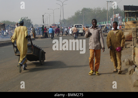 Pedestrians, man pulling a cart, cars and motorbikes, in the traffic and pollution of an african city Stock Photo