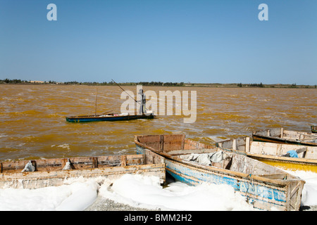 Senegal, Dakar. Man in a boat and boats on the salt filled shores of Lac Reba (Pink Lake) Stock Photo