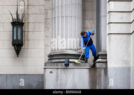 A cleaning janitor sweeps the base of columns in a government building, Buenos Aires, Argentina Stock Photo
