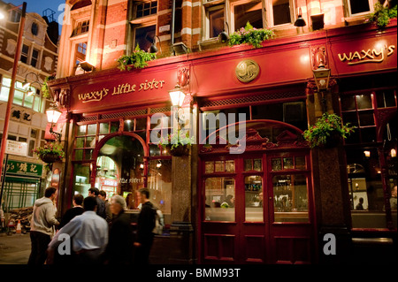 Medium Group People, Men Talking, Street Scene, Lights, Night, British Pubs, Bars, London, England, UK, Outside Pub, Storefronts 'Waxy's Little Sister' Sign, after work Stock Photo