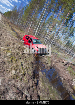 Crashed red VW Volkswagen Golf laying at roadside ditch at country road , Finland Stock Photo