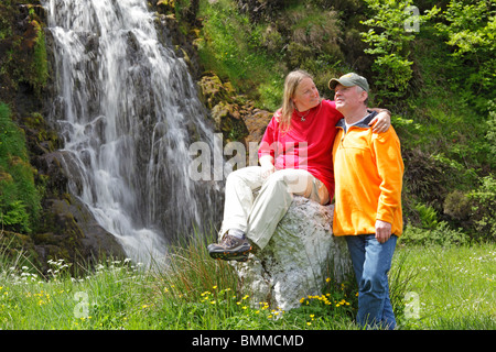 a couple posing in front of a waterfall near Ardara, Co. Donegal, Republic of Ireland Stock Photo