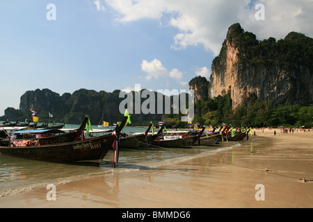 long tail boats on west Railay Beach, Tonsai, with cliff behind Stock Photo