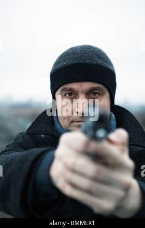 Man pointing a loaded handgun Stock Photo