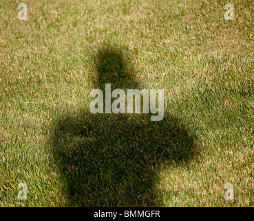 Image of the shadow of a photographer cast by the sun on a green lawn of mown grass Stock Photo