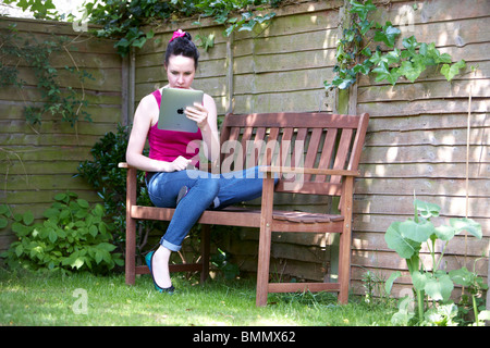 A woman uses a Ipad in the garden Stock Photo