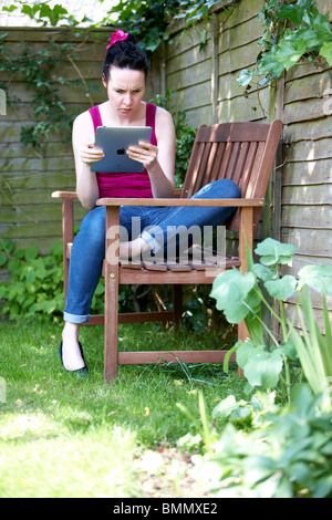 A woman uses a Ipad in the garden Stock Photo