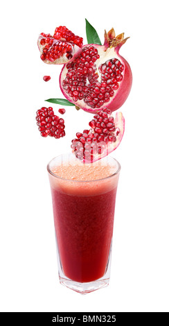Slices of pomegranate fall into a glass of fresh juice Stock Photo