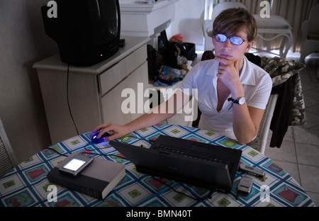 A young woman working with a computer with bluish screen reflections on her glasses Stock Photo