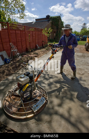 man levelling concrete base with power float Stock Photo