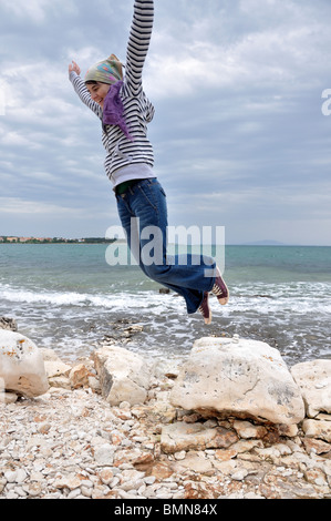 Young woman jumping in air, laughing, low angle view Stock Photo