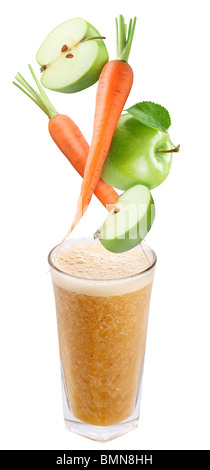 Slices of apple and carrot falling into a glass of fresh juice Stock Photo