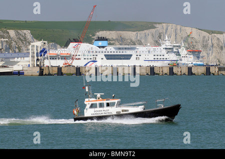 Dover Harbour pilot and patrol boat underway across Dover Harbour Kent England with a backdrop of the famous White Cliffs Stock Photo