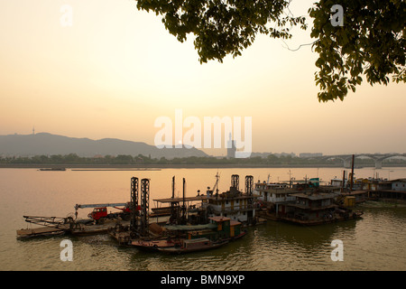 Sunset by the Xiang River in Changsha, Hunan province with docked barges in the foreground and mountain in the background Stock Photo