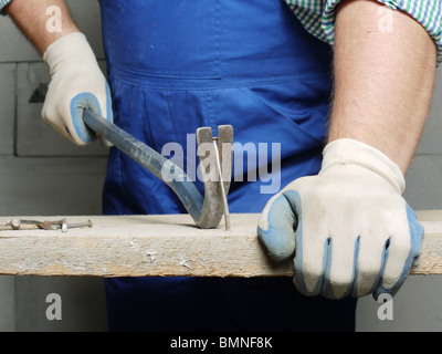Worker pulling a nail from a plank using wrecking bar Stock Photo