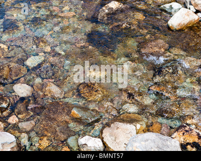 Pebbles in the water flowing in a stream close up overhead view Stock Photo