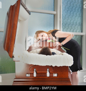 Edmonton, Alberta, Canada; A Young Woman Holds A Rose And Lays Her Head On The Coffin Of A Deceased Loved One Stock Photo