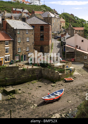 A steep side street in Staithes North Yorkshire leading down to Roxby Beck with a bright coloured fishing coble or boat Stock Photo