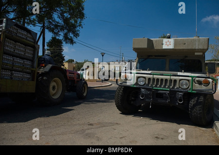 Israeli military ambulance HMMWV Humvee parked in a northern Israeli town with agricultural tractor passing by Stock Photo