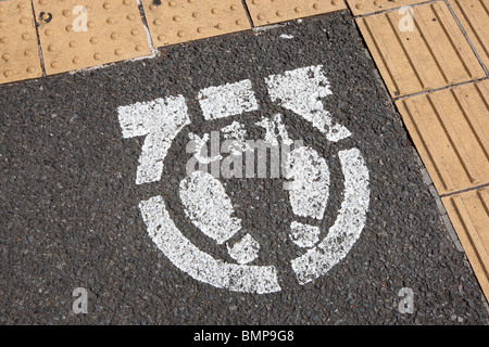 Road markings, including yellow raised markings to aid blind visually impaired people,  at pavement's edge, in Tokyo, Japan. Stock Photo