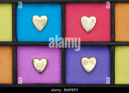 Multicoloured gold heart shape grid pattern in a wooden tray Stock Photo