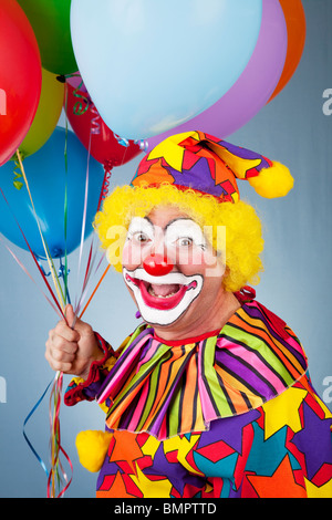 Portrait of happy clown holding a bunch of helium balloons.  Stock Photo