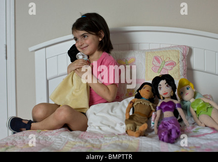 Hispanic 5 year old girl plays with Disney character dolls. Stock Photo