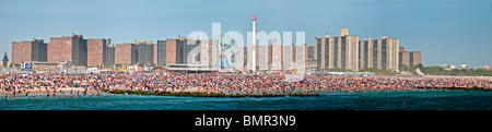 A holiday crowd of over a million sunbathes and swims on the beach of the famous Coney Island amusement park in Brooklyn, NYC Stock Photo