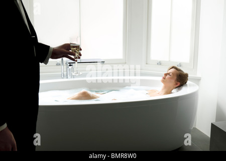Young woman taking a bath handed champagne Stock Photo