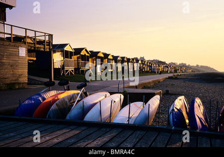 Sun setting across boats and beach huts in Whitstable, Kent, UK Stock Photo