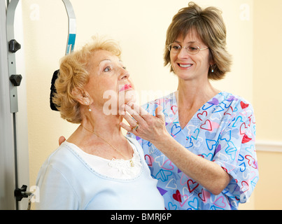 Physical therapist in chiropractors office helping a senior woman exercise her neck.  Stock Photo