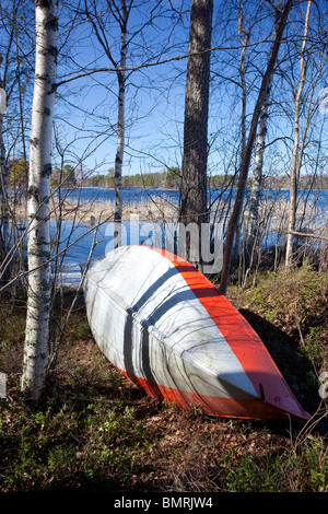 Aluminum rowboat / skiff / dinghy upside at lake shore , Finland Stock Photo